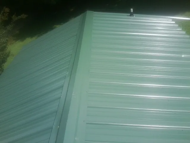 New green metal panels meeting at the ridge of a roof — Flat Roof Repair work by our crew in Pitman
