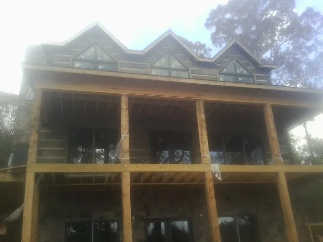 Dormers and porch framing on a large log home under construction — Roof Coating work by our crew in Pitman