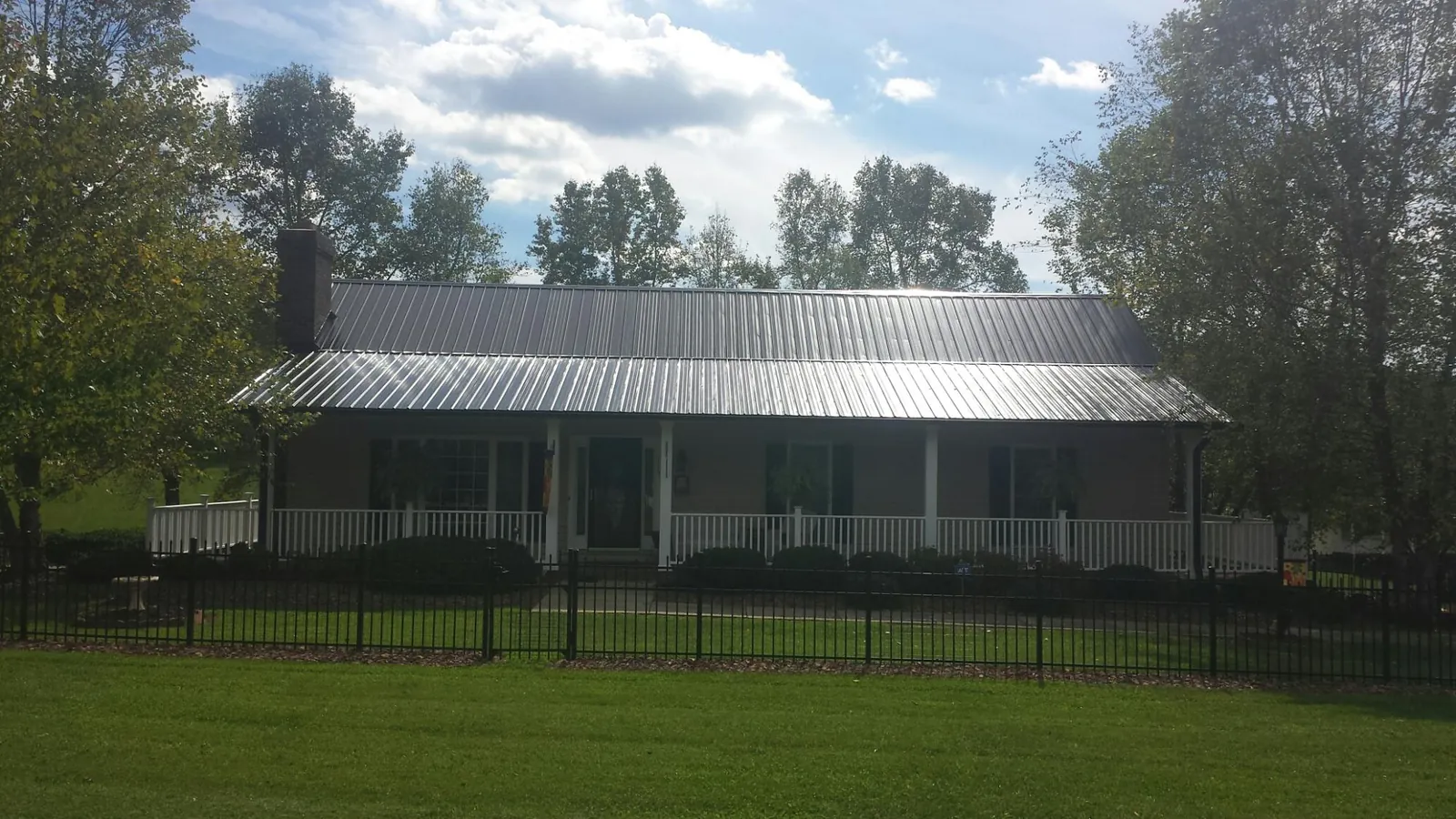 Gray metal roof on a brick ranch with a full width front porch — Gutter Guard Installation work by our crew in Pitman