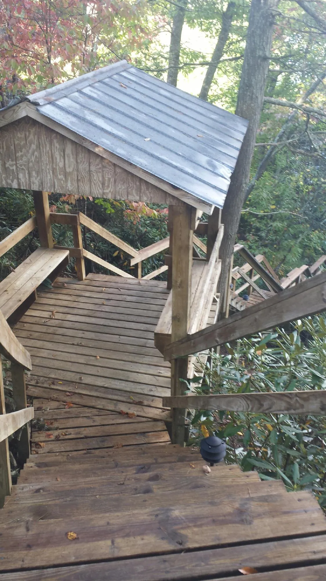 Metal roofed shelter over wooden steps on a wooded walkway — Skylight Repair & Installation work by our crew in Pitman